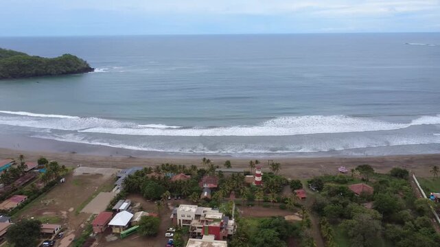 Aerial establishing shot of Playa Venao beach coastline with Pacific ocean waves, tropical lush greenery, and coastal buildings in Pedasi, Los Santos, Panama.