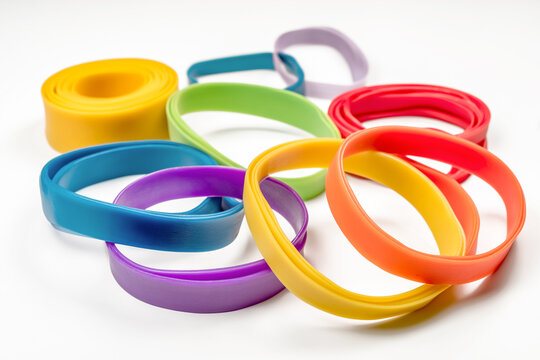 Colorful silicone wristbands and rubber elastic bands scattered on white background. Group of bright multicolored flexible fitness bracelets and sports gear