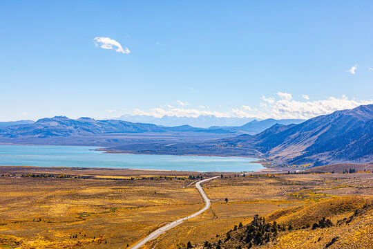 A winding road leads toward Mono Lake, framed by golden autumn hills and Sierra peaks.