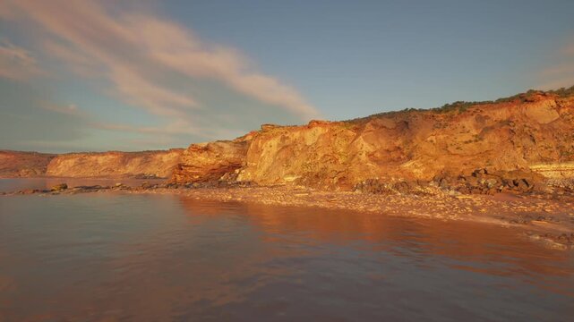 Golden sunset mood on cliffscape with reflective shallow water and drifting clouds, inviting inspirational captions for social, wellness, and lifestyle content