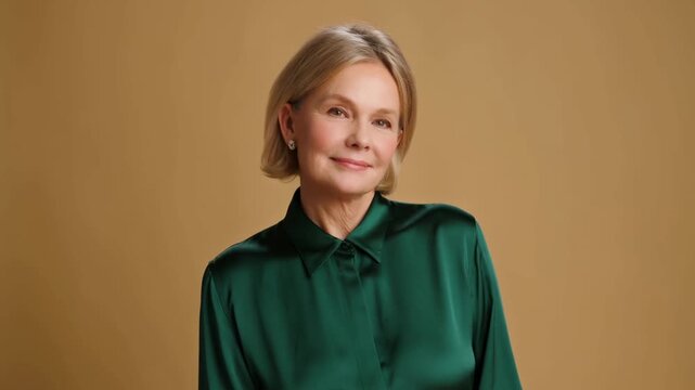 Mature Woman Standing and Looking Forward in Green Blouse Against Tan Studio Background