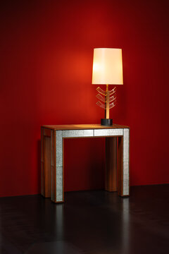 wooden console with textured mirrored glass inserts is topped by a sculptural table lamp with a fan-shaped stem in brass and glass.
