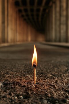 A single lit match cutting through a dark tunnel, symbolizing resilience, hope in despair, and the small spark that lights the way out of darkness