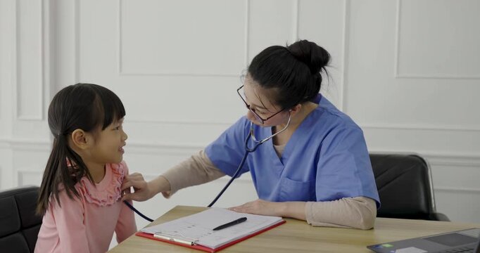 Young asian little toddler girl at the doctor's clinic. Asian doctor woman examining young girl with stethoscope pediatric checkup. Healthcare and medical sickness stress