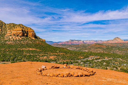 Sacred rock circle on slickrock red plateau overlooking panoramic desert valley and mountains at Airport Mesa vortex in Sedona, Arizona.