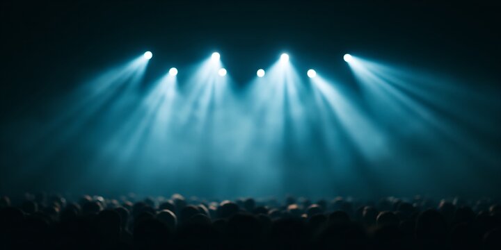 Theatrical stage lights illuminate audience in dark theater