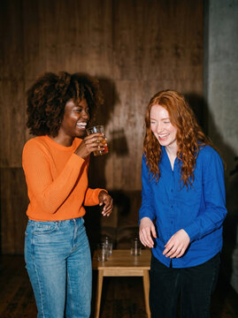Friends laugh together while drinking at a casual gathering
