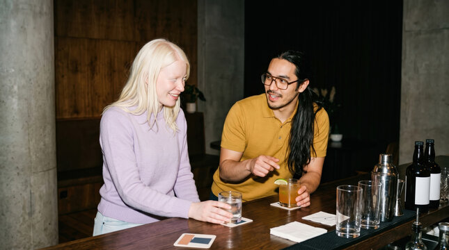 Friends enjoy cocktails at a bar counter after work