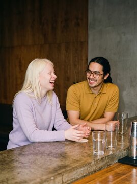 Two friends leaning on a bar counter chatting