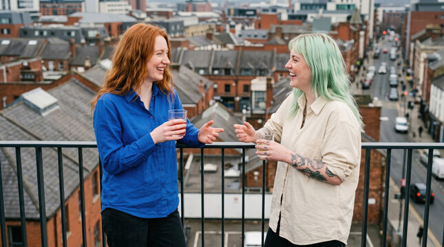 Two friends on a balcony with drinks above the city