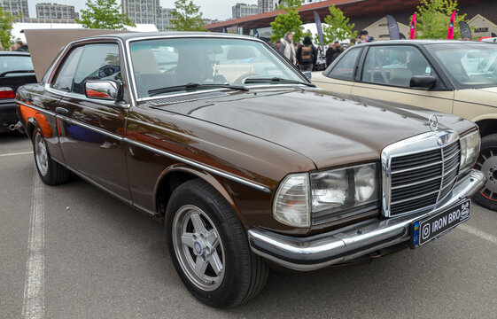 Classic Mercedes-Benz C123 coupe, a legendary icon of German engineering and luxury, showcases its pristine brown finish and elegant chrome details at car show