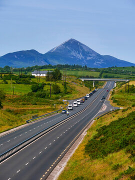 Motorway with a government car cartage and support vehicle, Famous Croagh Patrick in the background. International meeting and VIP travel to Ireland. High value cars. Warm sunny day.