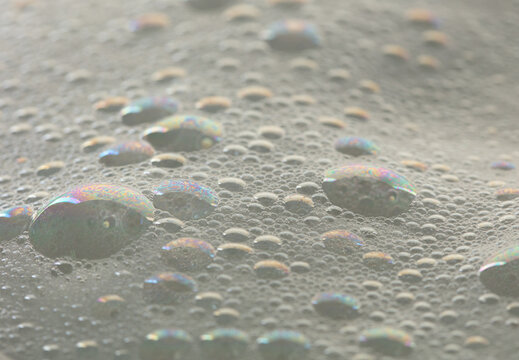 Many bubbles foam from soap bath shampoo shower gel on surface. Fluffy bath foam or beer bubble froth on surface wave curve texture form bubble