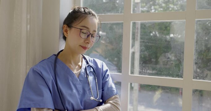 Female healthcare professional wearing scrubs and a stethoscope holding her forehead, expressing stress, fatigue, burnout, and mental pressure in a clinical setting.
