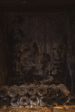 Deep in a Beaune wine cellar in Burgundy, France, aged bottles rest in darkness, coated with dust and cobwebs from decades of quiet maturation.