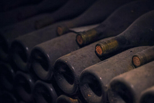 Dusty wine bottles lie in neat rows inside a Beaune cellar in Burgundy, France, symbolizing patience and heritage in winemaking.