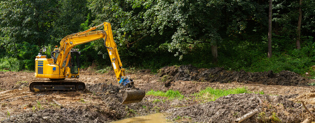 Excavator working in a forest panorama   Koparka pracująca na tle leśnej panoramy © Adrian White