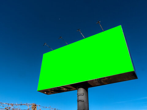 Large blank billboard with chroma key green screen structure on a metal pole under a clear blue sky, ideal for outdoor advertising mockup, commercial marketing template, and media message display