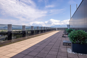 Fototapeta premium Modern rooftop terrace with tiled walkway glass railing and panoramic mountain landscape view