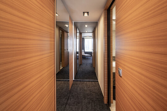 Modern interior hallway with wooden paneled doors mirrors and carpeted floor