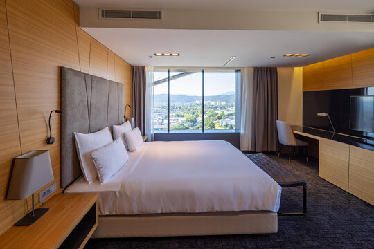 Luxury hotel suite bedroom with large king bed city view window and modern wooden interior