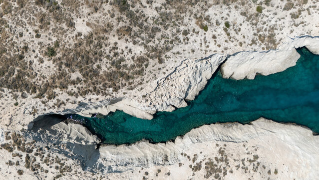 Aerial view of white coastal rocks surrounded by deep blue water near Mandrakia, Milos, Greece, showing the island&rsquo;s striking geology.