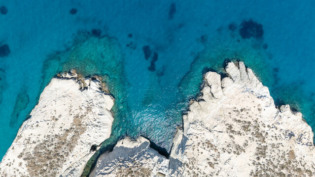 Aerial view of white coastal rocks surrounded by deep blue water near Mandrakia, Milos, Greece, showing the island&rsquo;s striking geology.