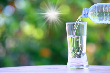glass of water. water flows into a glass on table and mineral water health. Close up the pouring purified fresh drink water from the bottle on table in living room. © Luis