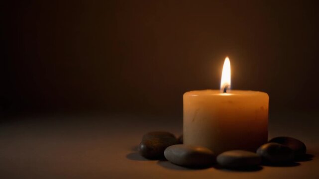 Peaceful Dark Room Scene with a Handmade Candle Flame and Smooth Natural Stones, Relaxing Zen Concept