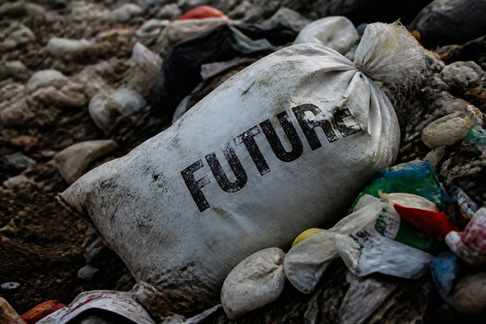A white sack labeled FUTURE rests amidst dirt, rocks, and scattered debris in an outdoor setting.