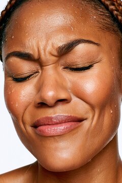 Close-up portrait of a woman scrunching her face with water droplets and expressive emotion