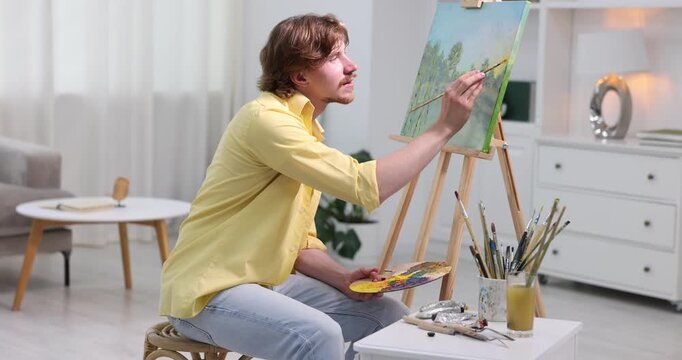 Man painting picture on easel in artist's studio