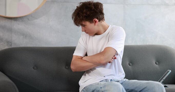 Teenager getting disgruntled while using tablet computer and putting it on sofa