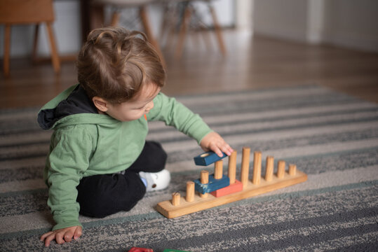Two-Year-Old Toddler Boy Playing with a Wooden Construction and Stacking Toy