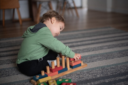 Two-Year-Old Toddler Boy Playing with a Wooden Construction and Stacking Toy