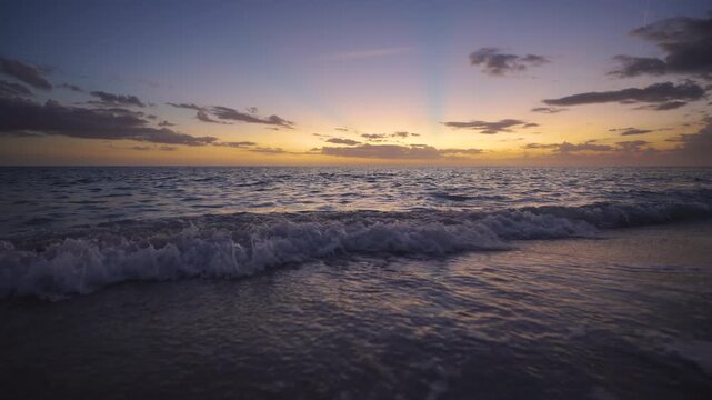 Calm seashore at twilight with soft waves, colorful sky reflections and tranquil atmosphere. Perfect tropical getaway scene with no people and peaceful mood.