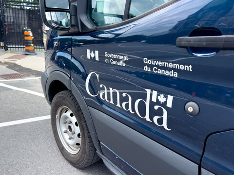 Ottawa, ON, Canada. Aug 20, 2026. Close-up view of official bilingual Government of Canada logo printed on the door of a dark blue van.