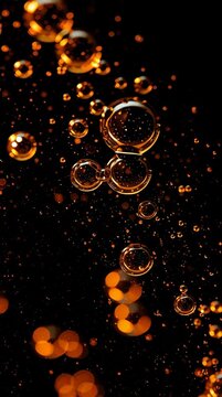 Droplets of oil float in dark water, shining bright amber. The activity shows the interaction of light with these suspended droplets.
