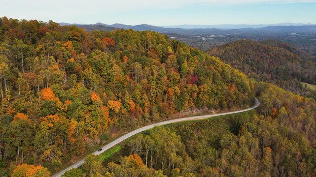 Road trip on mountain scenic route in North Carolina during peak fall season. Car drive at Appalachian landscape filled with vivid autumn colors.