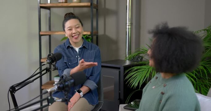 Asian woman responding to greeting, placing hand on chest, reaching, shaking hands by microphones