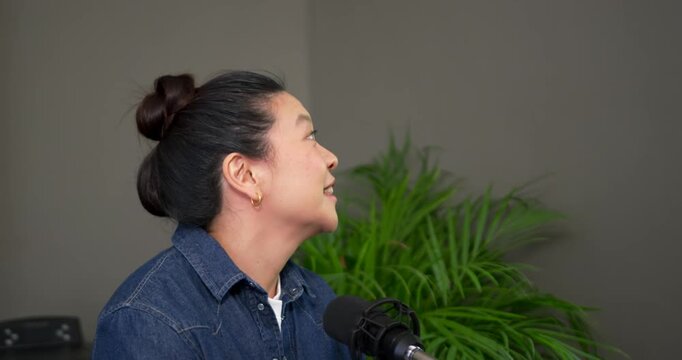 Woman in denim and stacked buns turning right at desk, speaking into mic after off-frame question
