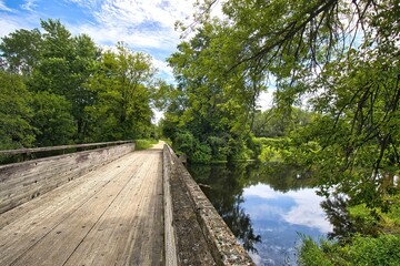 Fototapeta premium The Des Plaines River Trail crosses a trestle above reflecting water on a sunny summer day near Gurnee, Illinois.