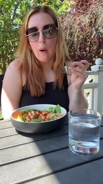 person eating a bowl of salad on a porch wearing sunglasses
