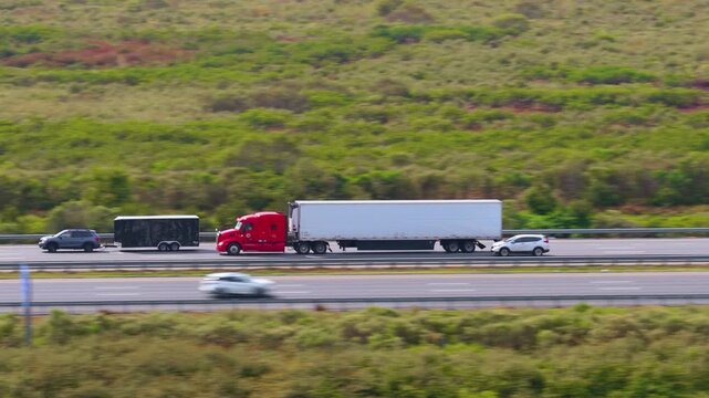 Heavy-duty big rig hauling goods across American freeway corridor. High speed freeway transportation.