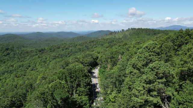 A single car traveling up a road winding through Oconee State Park with the foothills in the background in northwest South Carolina.