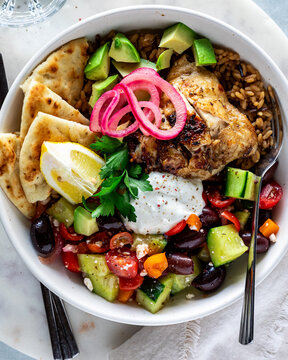 A top down view of a homemade Greek chicken bowl with Tzatziki sauce. 