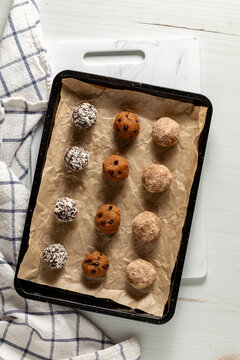 Rows of homemade high protein energy balls on a parchment lined cookie sheet. 