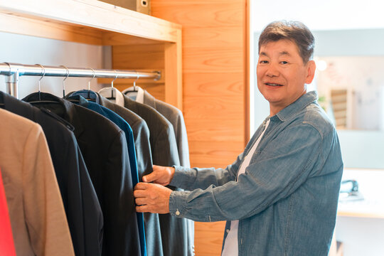 A senior man choosing clothes in the walk-in closet of his home.