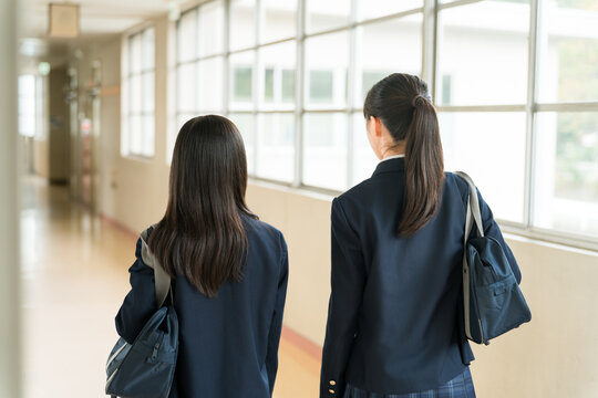 The back view of a friend walking down a school corridor (elementary school, middle school, and high school students, including female high school students, in their school uniforms)