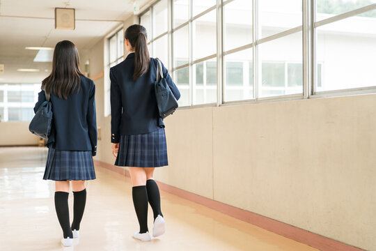 The back view of a friend walking down a school corridor (elementary school, middle school, and high school students, including female high school students, in their school uniforms)